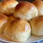 Golden brown, fluffy yeast rolls brushed with melted butter in a baking dish.