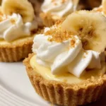 Individual no-bake mini banana cream pie topped with whipped cream and banana slices.