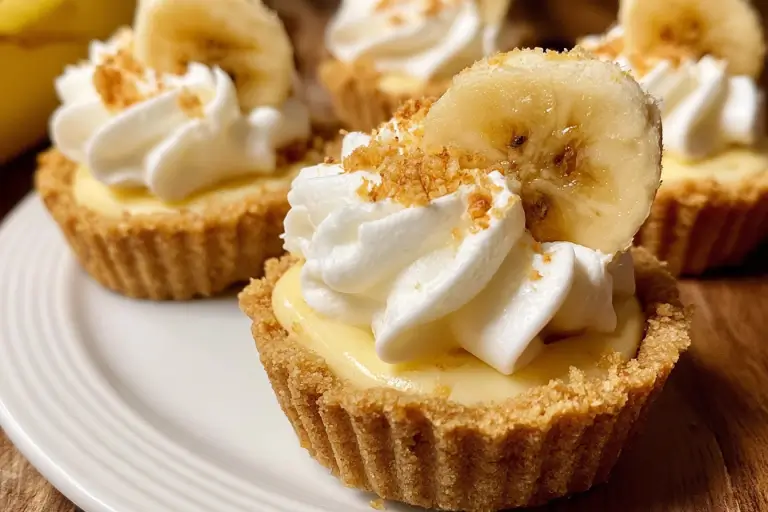 Individual no-bake mini banana cream pie topped with whipped cream and banana slices.
