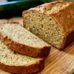 Freshly baked loaf of Greek yogurt zucchini bread sliced on a cooling rack.