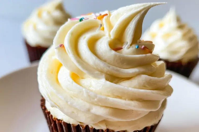 Fluffy white vanilla pudding frosting topped with sweet coconut flakes and colorful sprinkles.
