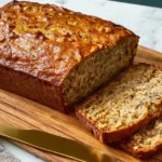Freshly baked moist banana bread loaf sliced on a cooling rack.