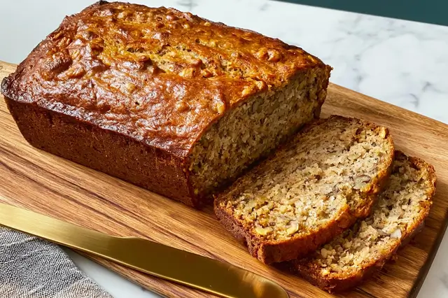 Freshly baked moist banana bread loaf sliced on a cooling rack.