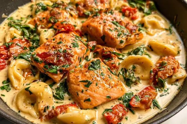 Creamy Tuscan salmon tortellini with spinach and garlic sauce served in a dish.