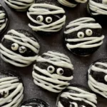 Black cocoa macaron shells filled with white chocolate ganache and decorated with candy eyes