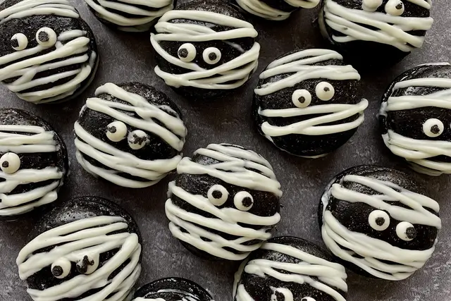 Black cocoa macaron shells filled with white chocolate ganache and decorated with candy eyes