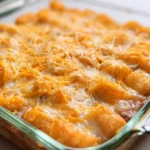 Baked ground beef tater tot casserole with melted cheddar cheese in a baking dish.