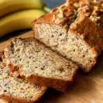 Golden-brown loaf of homemade banana bread sliced in a baking pan.