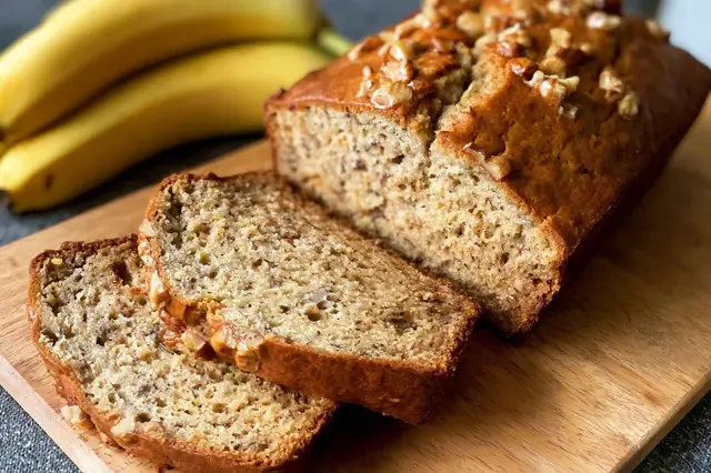 Golden-brown loaf of homemade banana bread sliced in a baking pan.
