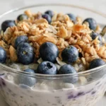 Creamy blueberry crunch overnight oats topped with fresh blueberries and crunchy granola