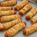 Hot Dog Mummies: Spooky Fun for Your Next Party 5 Baked hot dog mummies wrapped in golden crescent roll dough strips.