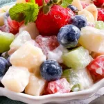 Delicious creamy fruit salad bowl filled with fresh fruit